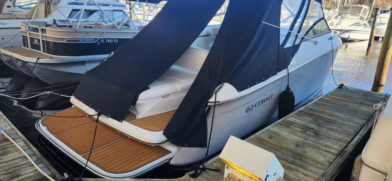 Slide: The Image of 2010 Cobalt 323 boat docked, featuring a sleek design and covered seating area. - 2