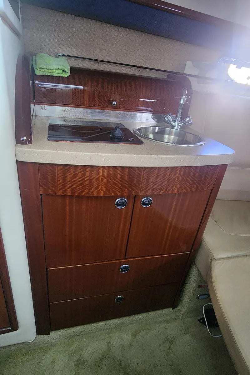Slide: The Image of 2010 Cobalt 323 boat interior with wooden cabinetry and compact kitchenette. - 33