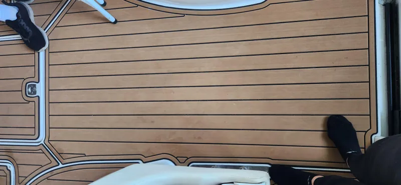 Slide: The Image of Teak deck of a 2010 Cobalt 323 boat with visible feet and chair. - 49