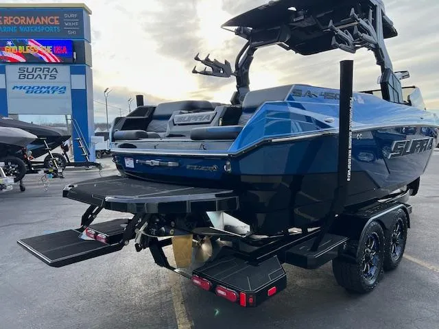 Slide: The Image of 2025 Supra SA450 boat, blue, on trailer at dealership, rear view. - 7