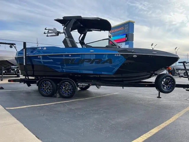 Slide: The Image of 2025 Supra SA450 boat on trailer, blue and black design, parked outdoors. - 8