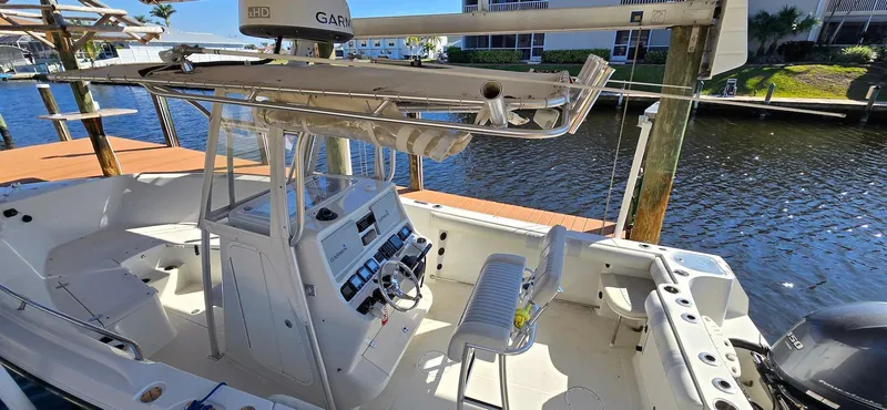Slide: The Image of 2011 Sailfish 2360 CC boat interior with console and seating, docked by the water. - 10