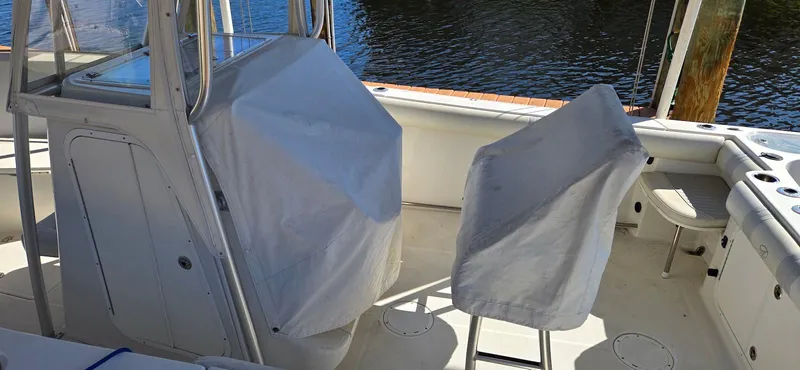 Slide: The Image of 2011 Sailfish 2360 CC boat interior with covered seats and console, docked by water. - 16