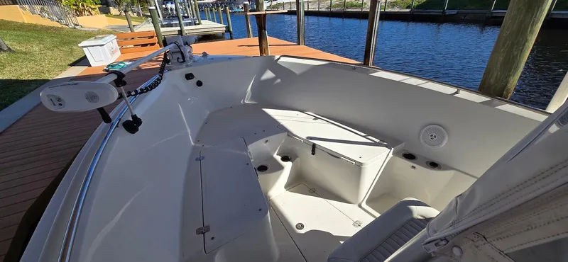 Slide: The Image of 2011 Sailfish 2360 CC boat interior, featuring spacious seating and modern design by the dock. - 17