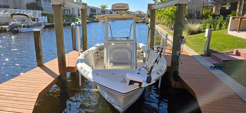 Slide: The Image of 2011 Sailfish 2360 CC boat docked in a sunny canal setting. - 2