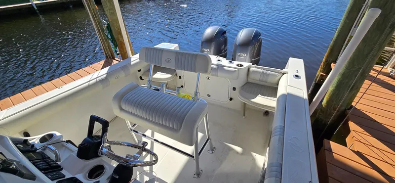 Slide: The Image of 2011 Sailfish 2360 CC boat interior with dual outboard motors, docked by wooden pier. - 3