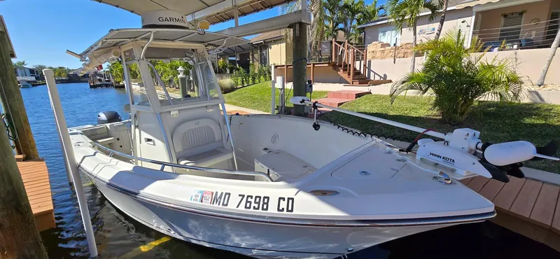 Slide: The Image of 2011 Sailfish 2360 CC boat docked by waterfront home, featuring center console and outboard motor. - 4