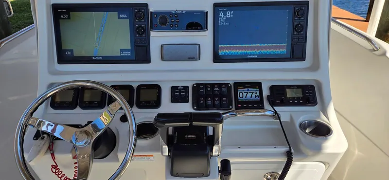 Slide: The Image of Control panel of a 2011 Sailfish 2360 CC boat with navigation screens and steering wheel. - 6