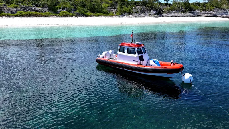 Slide: The Image of A 2003 Zodiac Hurricane boat anchored near a pristine beach with clear blue water. - 1