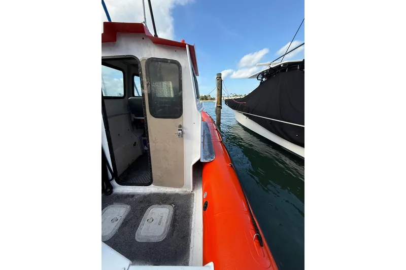 Slide: The Image of 2003 Zodiac Milpro Hurricane boat docked, showing cabin entrance and vibrant orange exterior. - 13