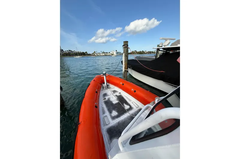 Slide: The Image of 2003 Zodiac Milpro Hurricane boat docked on calm water under a clear blue sky. - 15