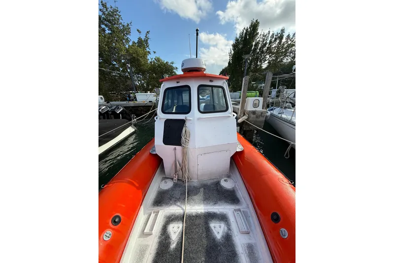 Slide: The Image of 2003 Zodiac Milpro Hurricane boat docked, featuring orange inflatable sides and a white cabin. - 16