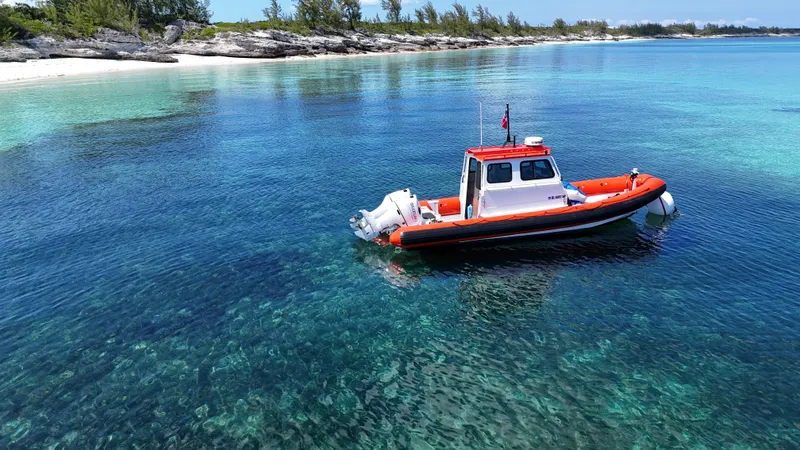 Slide: The Image of A 2003 Zodiac Hurricane boat on clear turquoise water near a rocky shoreline. - 3