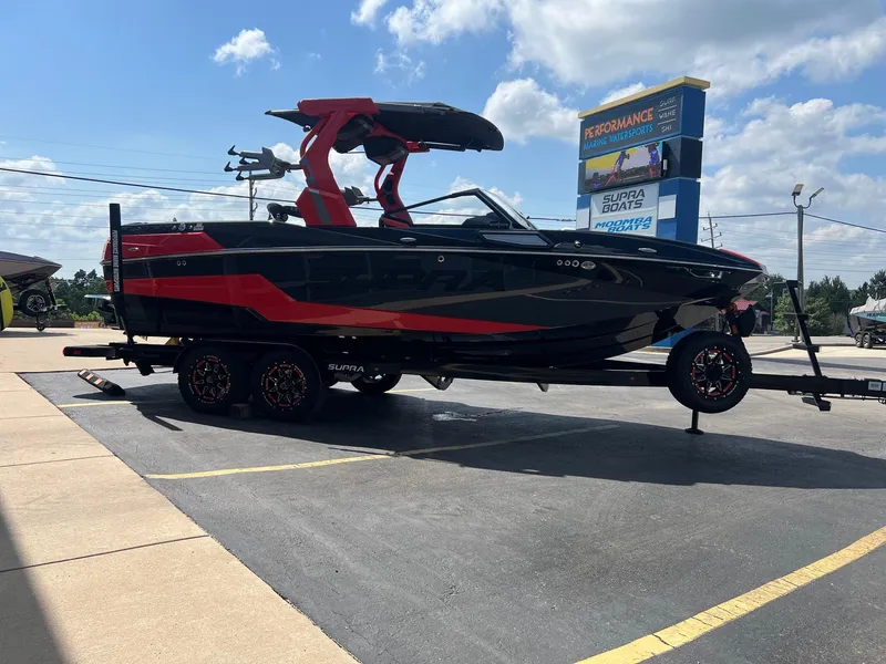 Slide: The Image of 2025 Supra SL450 boat with red and black design on a trailer at a dealership. - 5