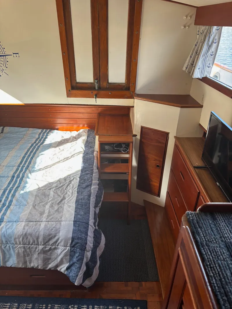Slide: The Image of 1982 Grand Banks 36 Classic cabin interior with bed, wooden cabinetry, and TV. - 15