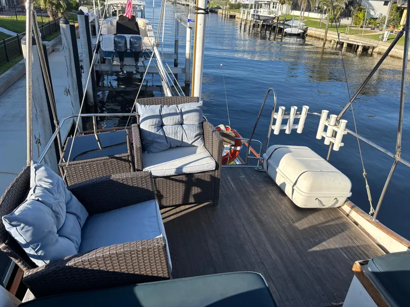 Slide: The Image of 1982 Grand Banks 36 Classic yacht deck with wicker seating, docked by a serene waterfront. - 20