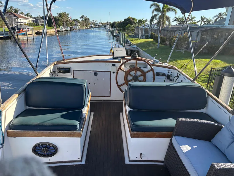 Slide: The Image of 1982 Grand Banks 36 Classic boat interior with canal view, featuring wooden steering wheel and seating. - 21