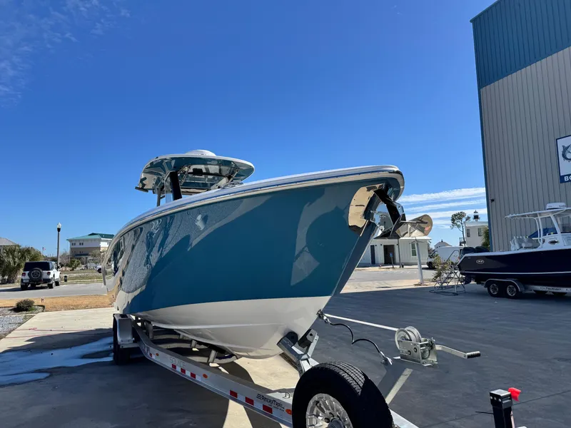 Slide: The Image of 2025 Solace 32 CS boat on trailer, blue hull, parked outdoors under clear sky. - 10