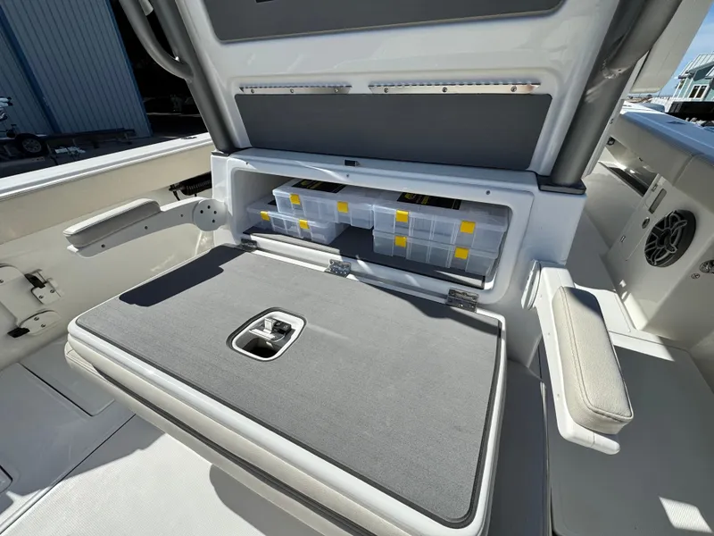 Slide: The Image of 2025 Solace 32 CS boat storage compartment with organized tackle boxes and seating. - 16