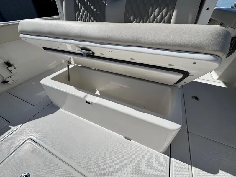 Slide: The Image of Open storage compartment on 2025 Solace 32 CS boat, featuring cushioned seating. - 17