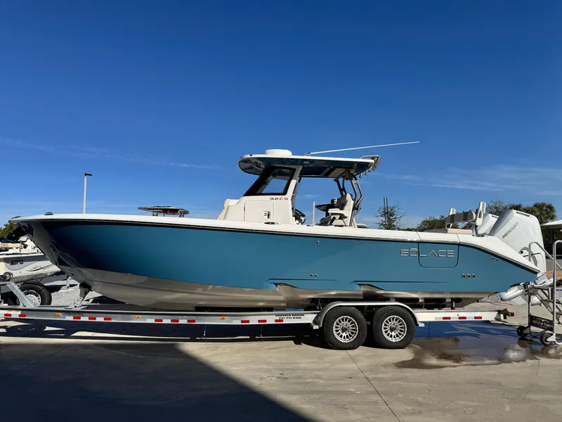 Slide: The Image of 2025 Solace 32 CS boat on trailer, blue hull, parked outdoors under clear sky. - 3