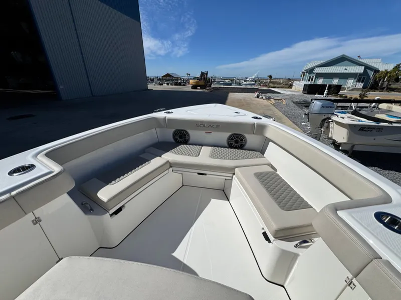 Slide: The Image of 2025 Solace 32 CS boat interior with cushioned seating and cup holders, dockside view. - 32