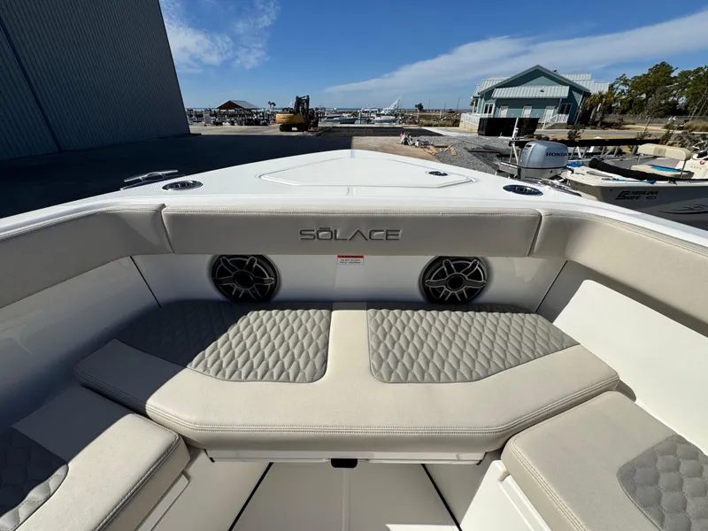 Slide: The Image of 2025 Solace 32 CS boat interior with cushioned seating and speakers, dockside view. - 33