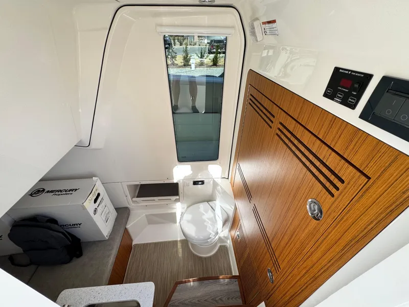 Slide: The Image of Interior of 2025 Solace 32 CS boat featuring a compact bathroom with wooden accents. - 37