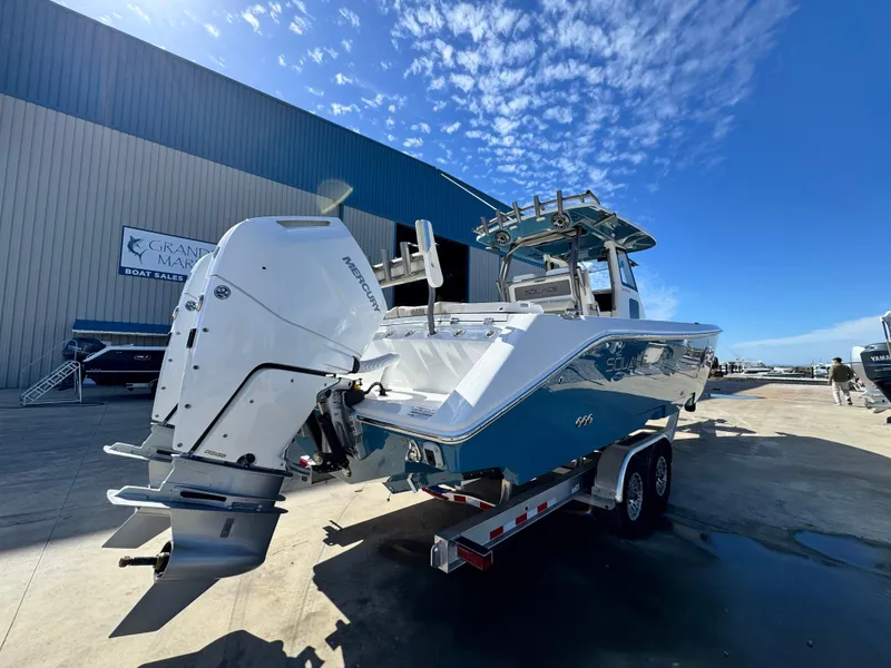 Slide: The Image of 2025 Solace 32 CS boat with powerful outboard engine on trailer, parked outside a warehouse. - 6