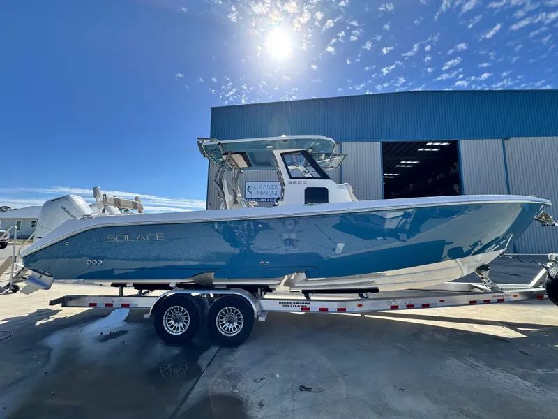 Slide: The Image of 2025 Solace 32 CS boat on trailer under sunny sky, near industrial building. - 8