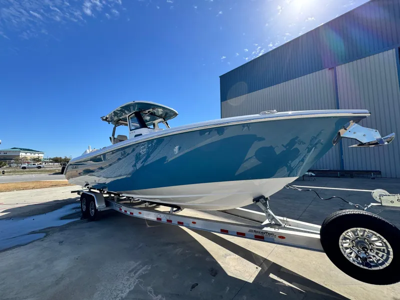 Slide: The Image of 2025 Solace 32 CS boat on trailer, blue hull, parked outdoors near a large building. - 9