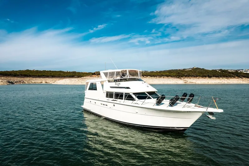 Slide: The Image of 1998 Hatteras 52 Sport Deck Motor Yacht on serene water under blue sky. - 48