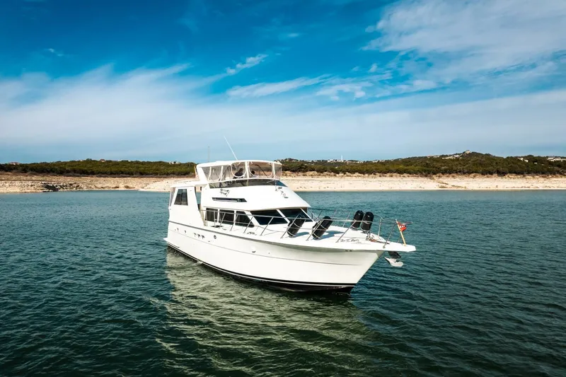Slide: The Image of 1998 Hatteras 52 Sport Deck Motor Yacht on calm water under blue sky. - 49