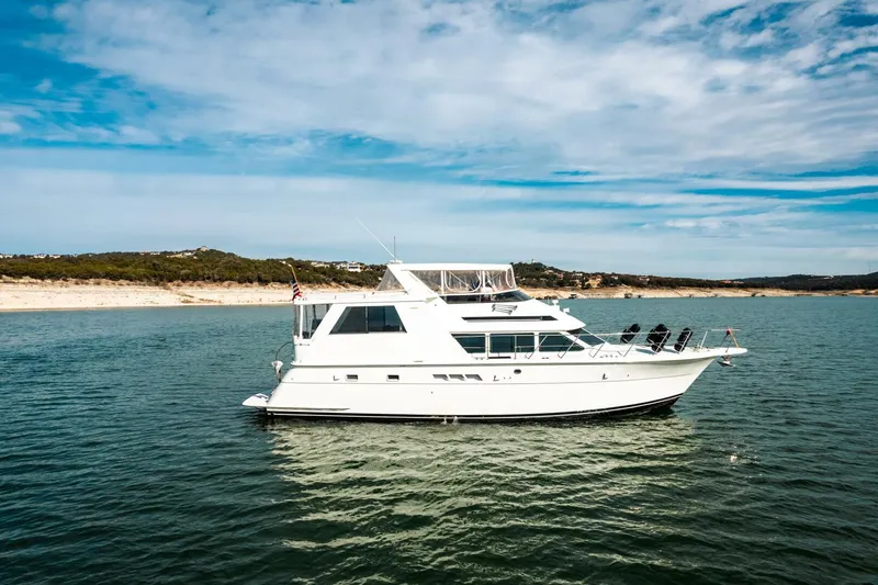 Slide: The Image of 1998 Hatteras 52 Sport Deck Motor Yacht on calm water under a blue sky. - 50