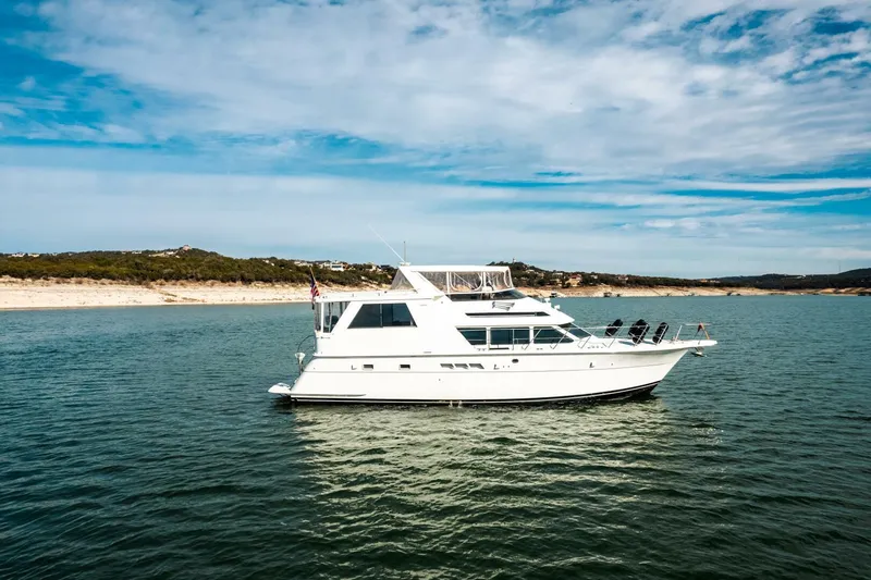 Slide: The Image of 1998 Hatteras 52 Sport Deck Motor Yacht on serene water under blue sky. - 51