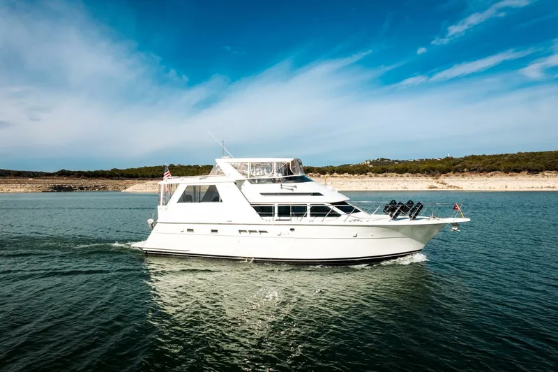 Slide: The Image of 1998 Hatteras 52 Sport Deck Motor Yacht cruising on open water under clear skies. - 56