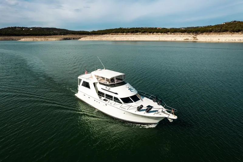 Slide: The Image of 1998 Hatteras 52 Sport Deck Motor Yacht cruising on a serene lake. - 58