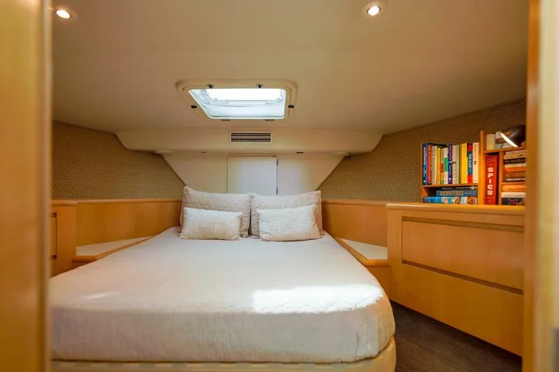 Slide: The Image of 1998 Hatteras 52 Sport Deck Motor Yacht bedroom with skylight, cozy bed, and bookshelf. - 6