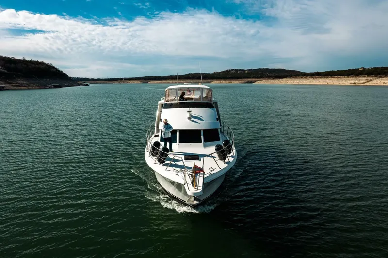 Slide: The Image of 1998 Hatteras 52 Sport Deck Motor Yacht cruising on a serene lake. - 61