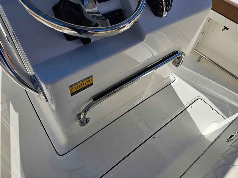 Slide: The Image of 2025 Pioneer 222 Sportfish boat console with steering wheel and stainless steel grab rail. - 16