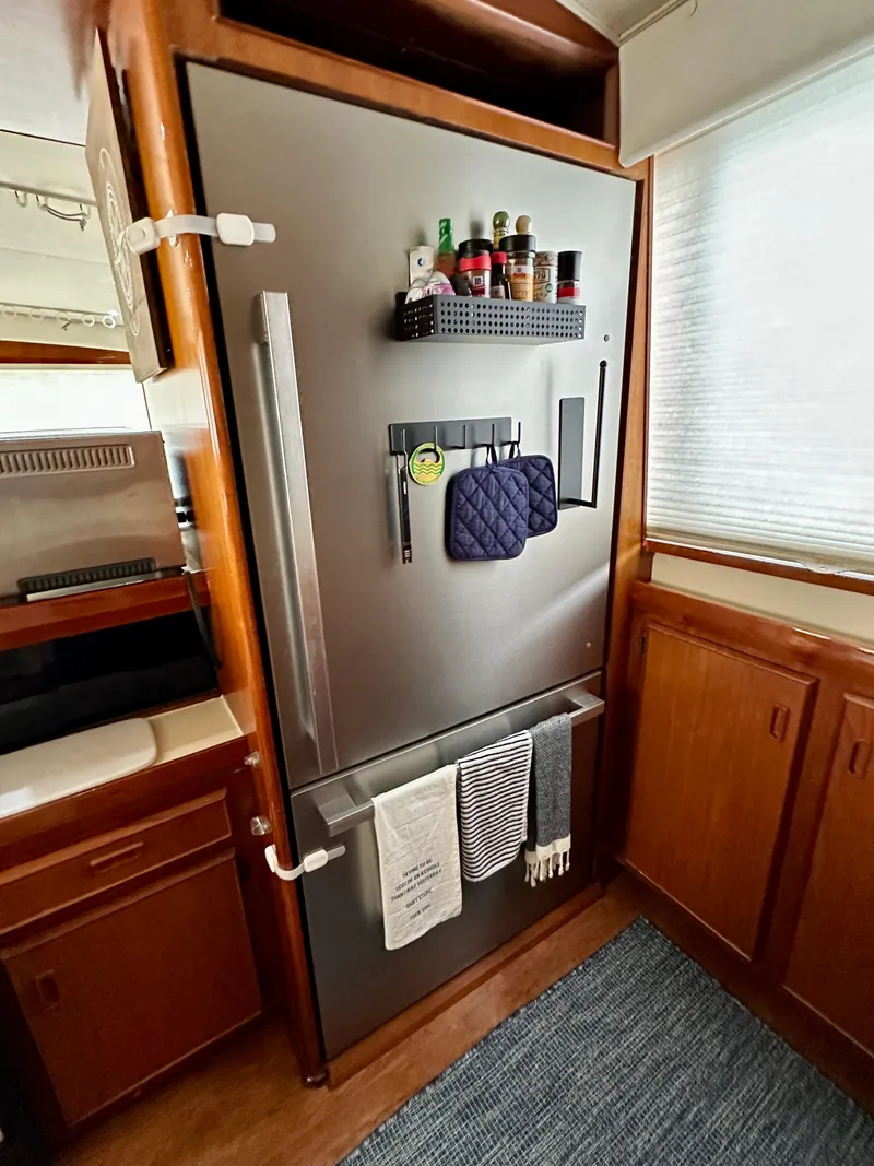 Slide: The Image of Modern kitchen area in a 1982 Bertram 54 Convertible yacht, featuring a stainless steel refrigerator. - 22