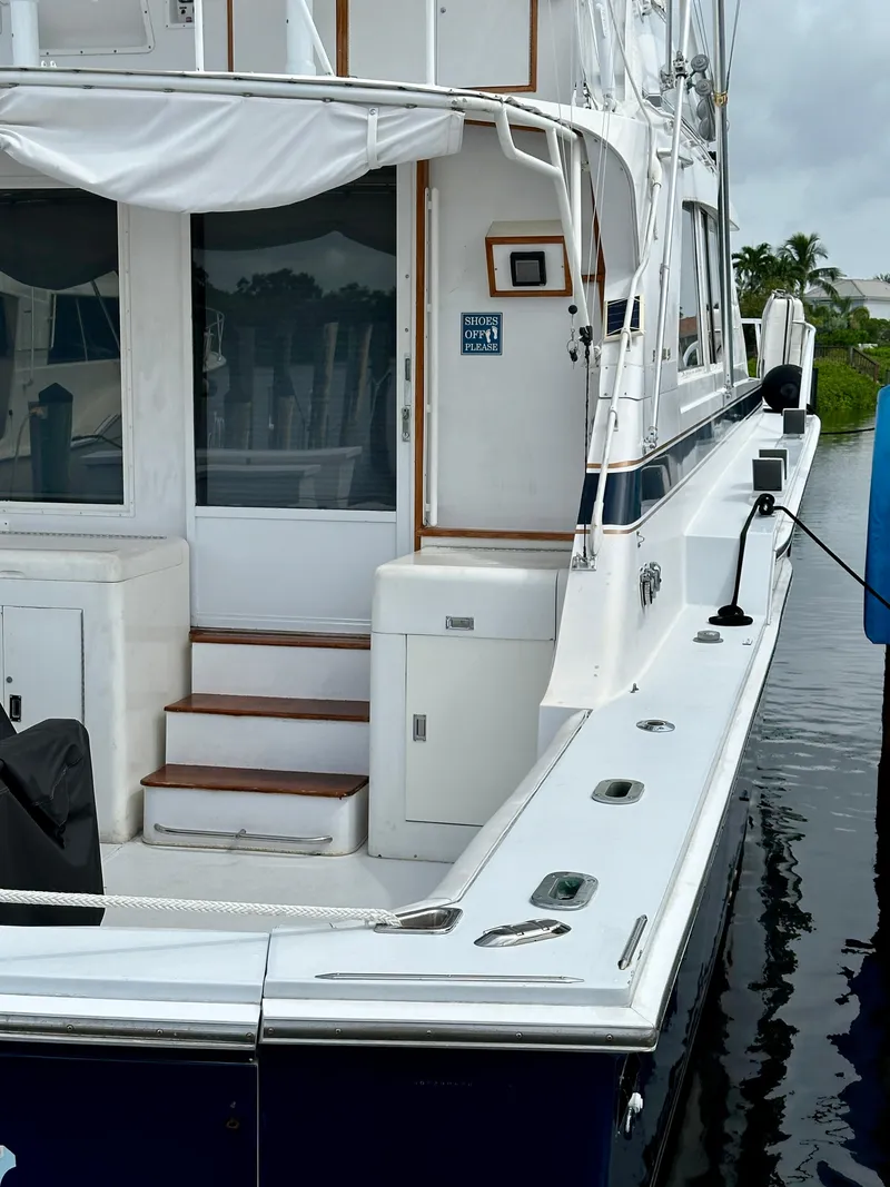 Slide: The Image of 1982 Bertram 54 Convertible yacht docked, featuring white exterior and wooden steps. - 3