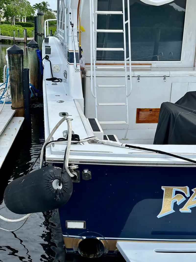 Slide: The Image of 1982 Bertram 54 Convertible yacht docked, featuring a ladder and fender. - 4