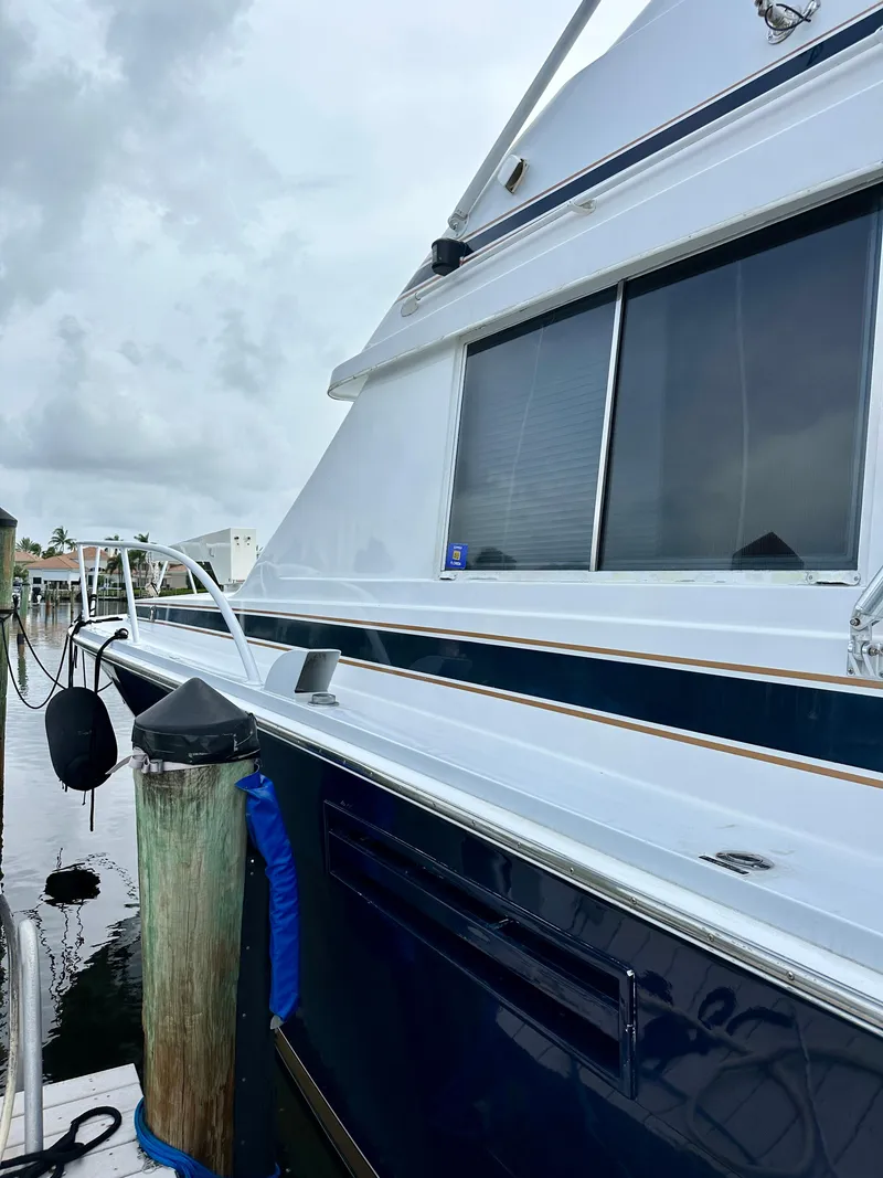 Slide: The Image of 1982 Bertram 54 Convertible yacht docked, showcasing sleek design and windows. - 6