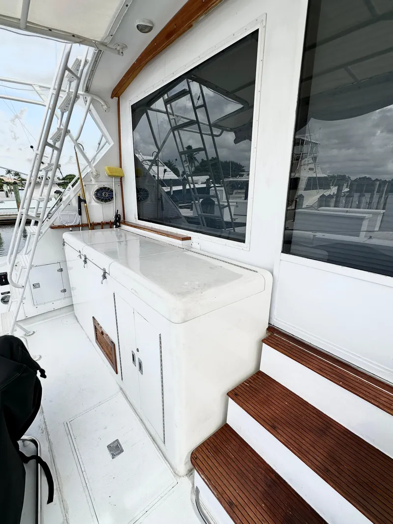 Slide: The Image of 1982 Bertram 54 Convertible yacht deck with white cabinetry and wooden steps. - 9