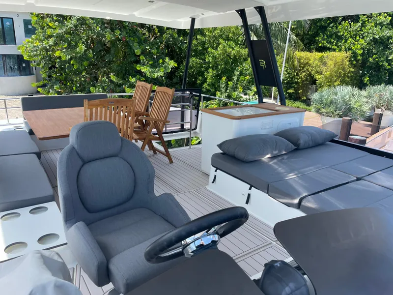 Slide: The Image of Luxurious 2020 Fountaine Pajot MY 44 yacht interior with seating, dining area, and lush greenery backdrop. - 20