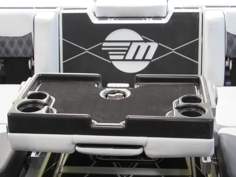 Slide: The Image of 2025 Malibu M230 boat interior with a sleek black and white table featuring cup holders. - 16