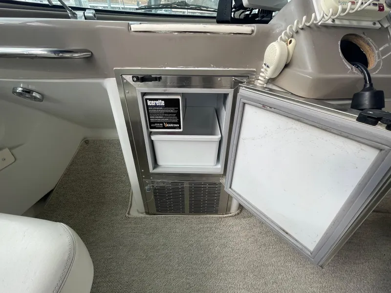 Slide: The Image of 2002 Carver 350 Mariner interior with open mini fridge and beige carpet. - 12