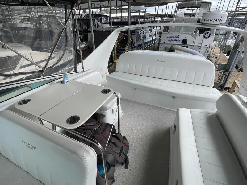 Slide: The Image of 2002 Carver 350 Mariner yacht interior with white seating and table, docked in marina. - 14