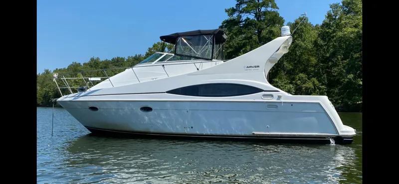 Slide: The Image of 2002 Carver 350 Mariner yacht on a serene lake with lush green trees. - 2